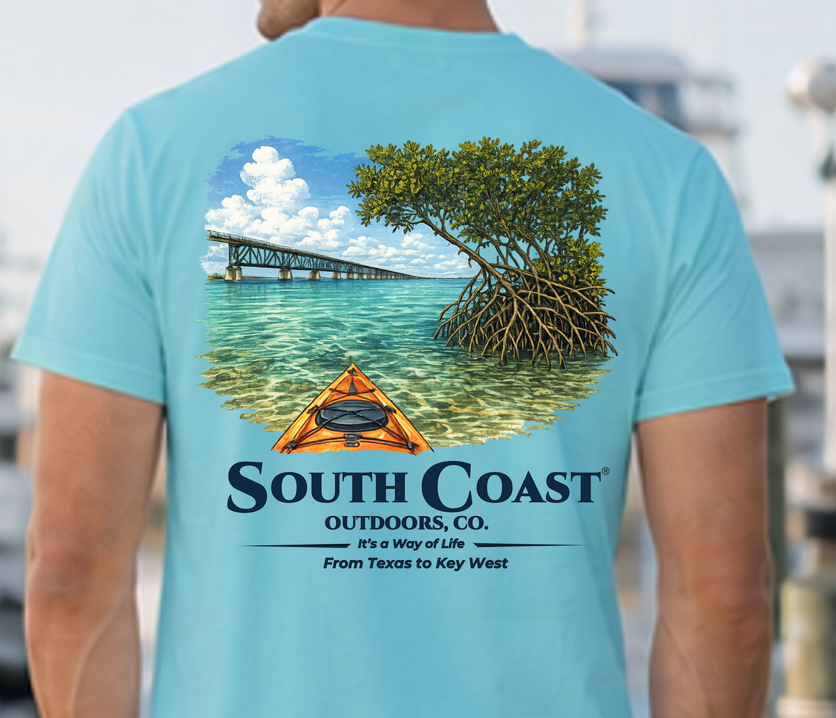 Light blue T-shirt back graphic: mangrove trees, orange kayak, South Coast Outdoors.