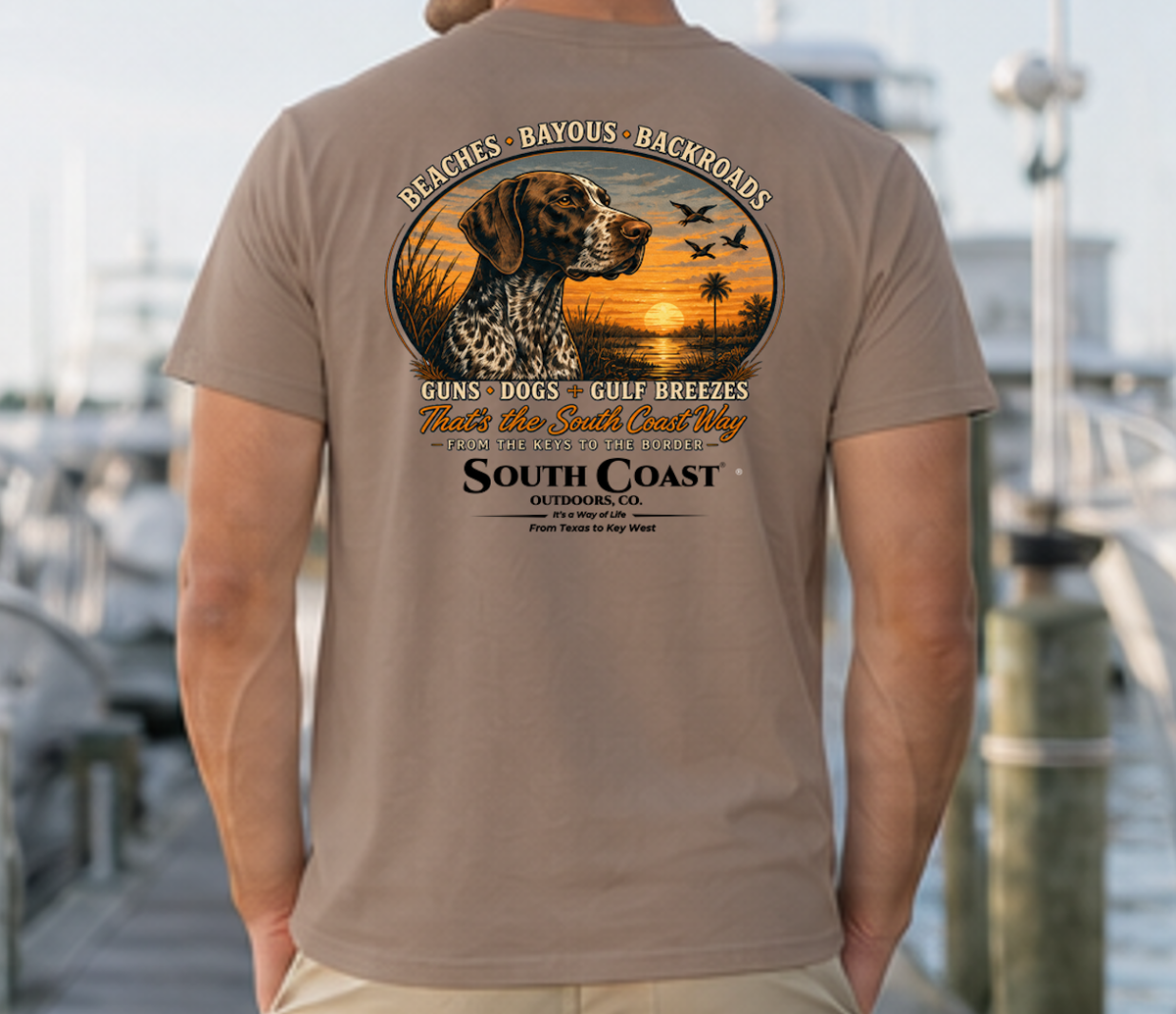 Taupe T-shirt with circular animal sunset graphic and “South Coast Outdoors” back print