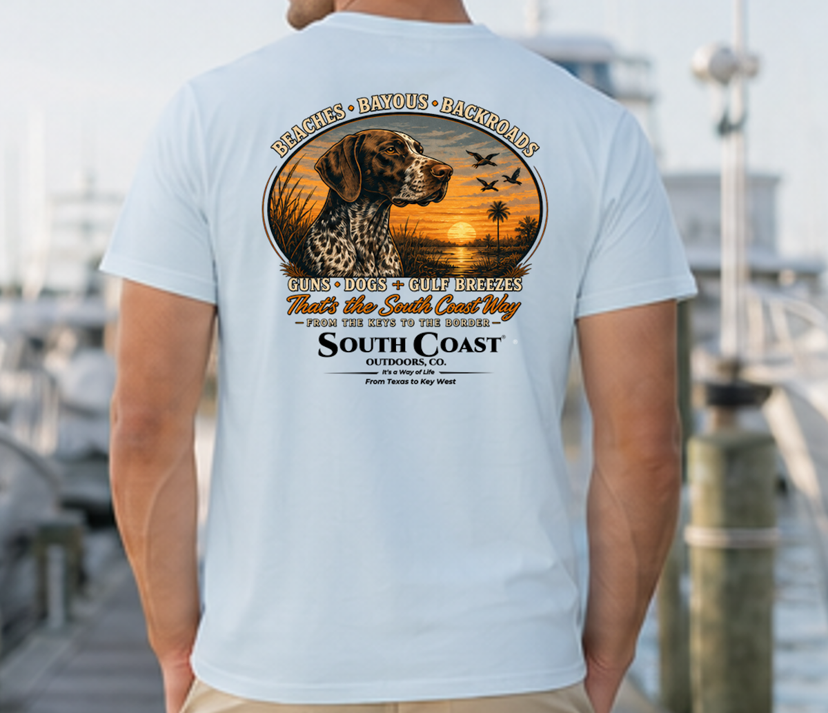 Light blue T-shirt with circular animal sunset graphic and “South Coast Outdoors” back print