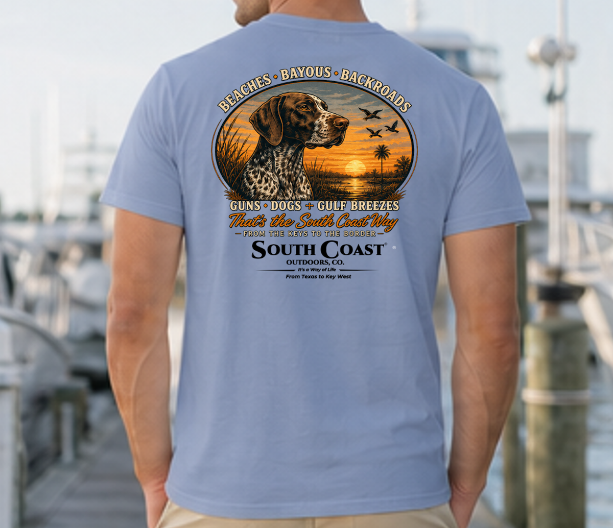 Blue T-shirt with circular animal sunset graphic and “South Coast Outdoors” back print