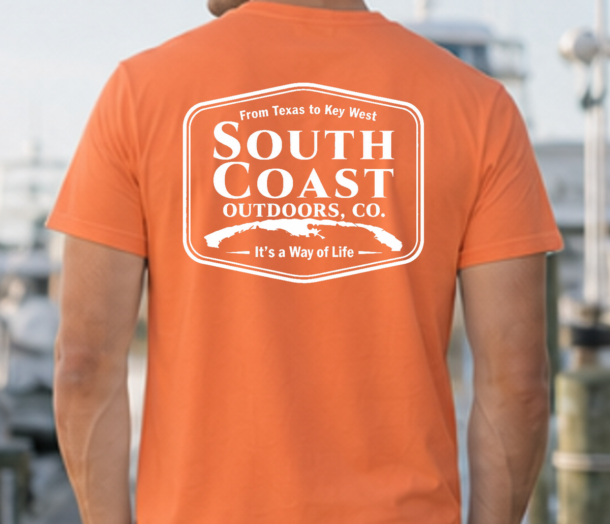 Orange T-shirt with large white South Coast Outdoors logo badge on back.